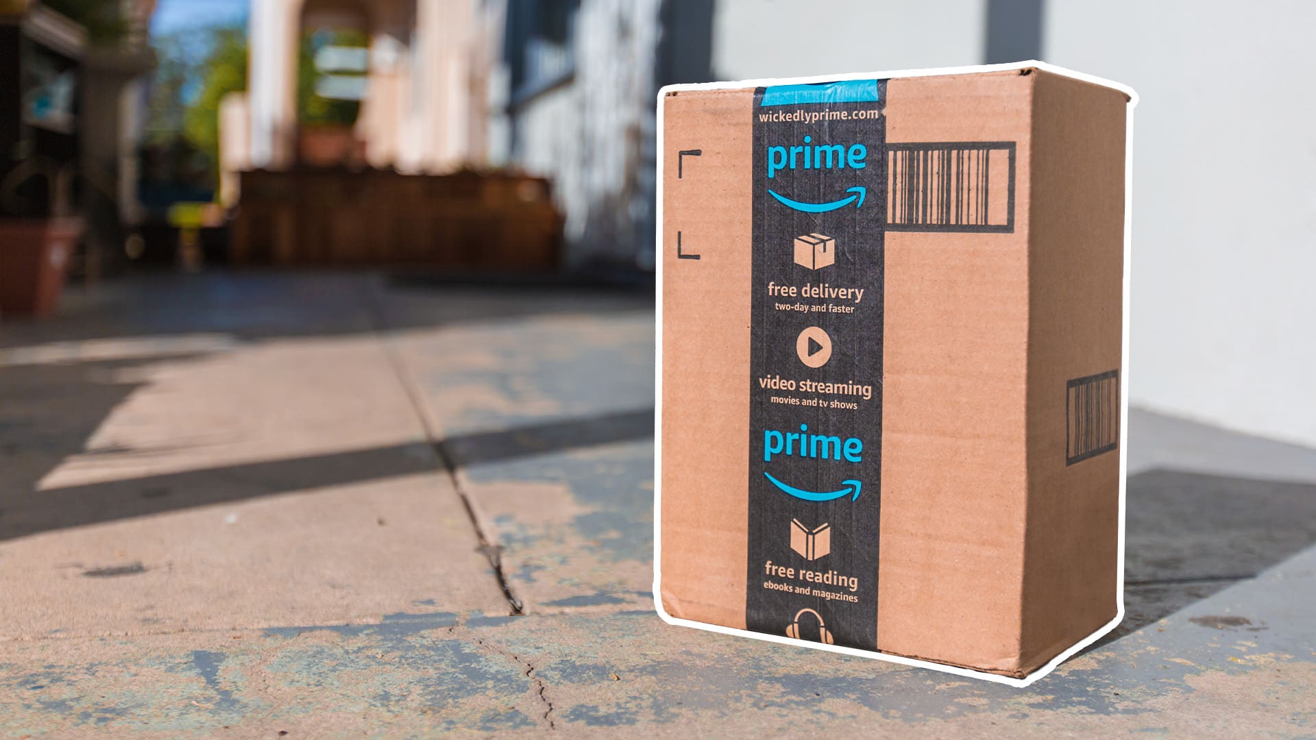 A medium sized Amazon prime box sitting on the street with a white outline.
