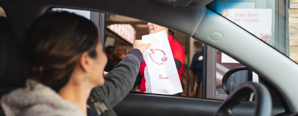 woman picking up Chick Fil A from drive thru window