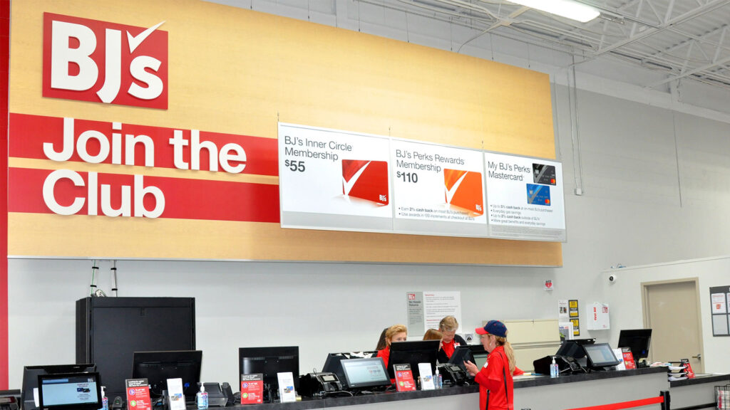 BJ's Wholesale membership counter showing workers processing new memberships. Membership prices are shown as bannerss above the counter, which include Inner Circle memberships for $55 , BJs Perks Rewards MEmbership for $110 and BJ's Perk Mastercard. 
